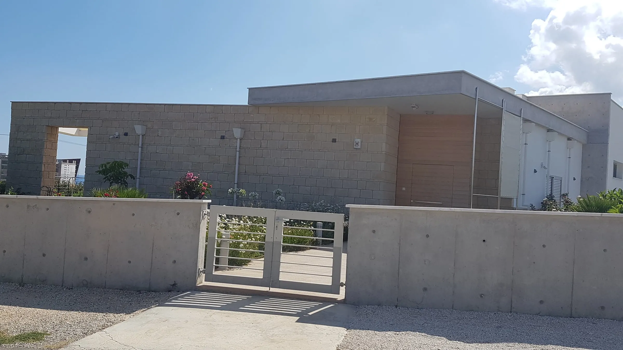 Completed contemporary residence in Latchi with cut-stone walls, exposed concrete and a timber entrance door